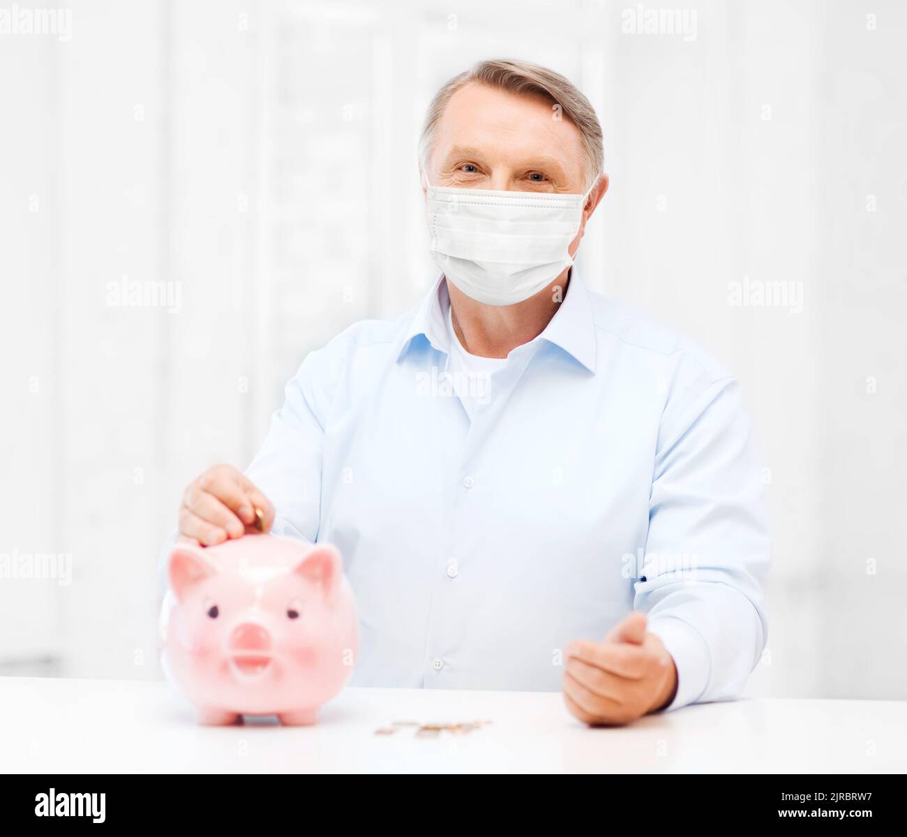 old man in mask putting coin into big piggy bank Stock Photo - Alamy