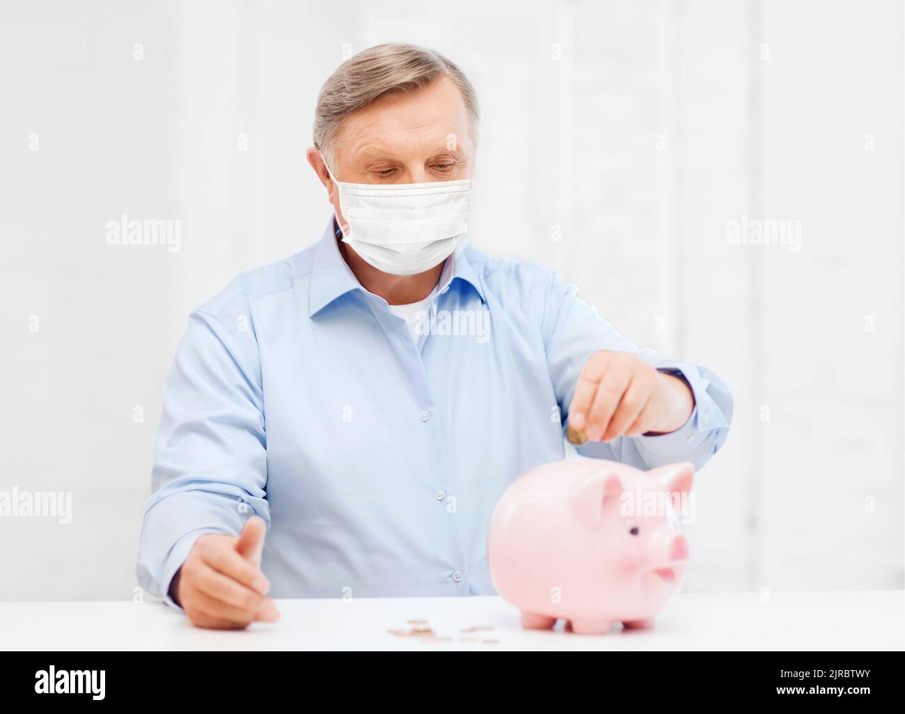 old man in mask putting coin into big piggy bank Stock Photo - Alamy