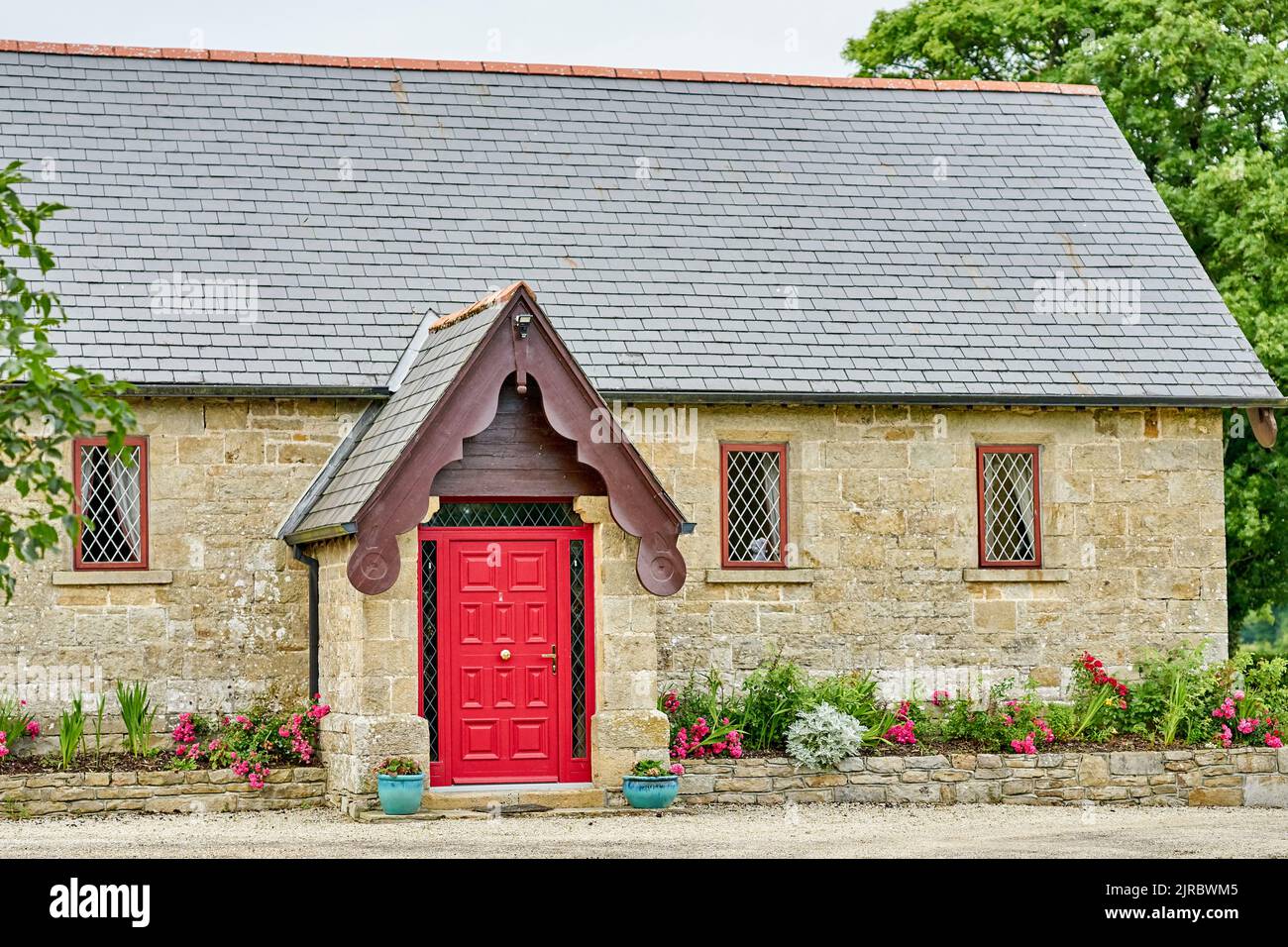 A beautiful stone house with a red door and flower garden, in Ireland. Stock Photo