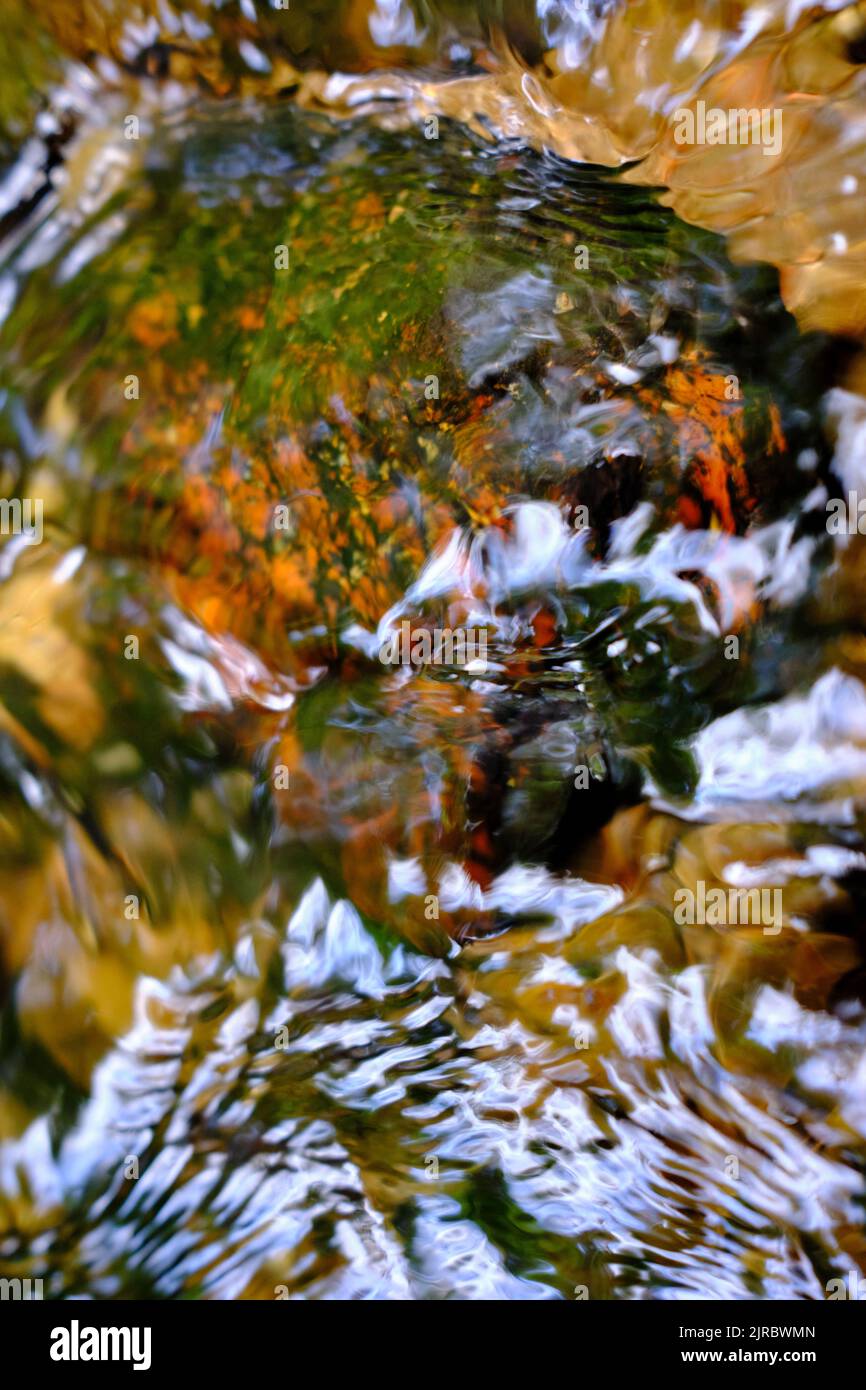 Colored rocks, waters flow and sun reflections in a creek in close-up Stock Photo