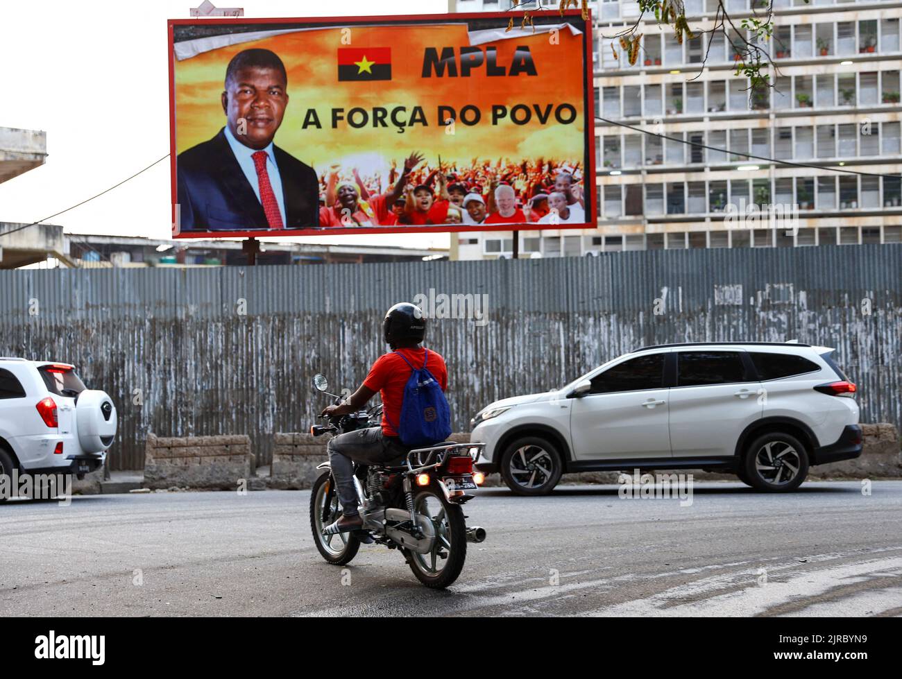 A motorcyclist rides past a billboard with the face of Angola's President and leader of the ruling MPLA party, ahead of elections in the capital Luanda, Angola August 23, 2022. REUTERS/Siphiwe Sibeko Stock Photo