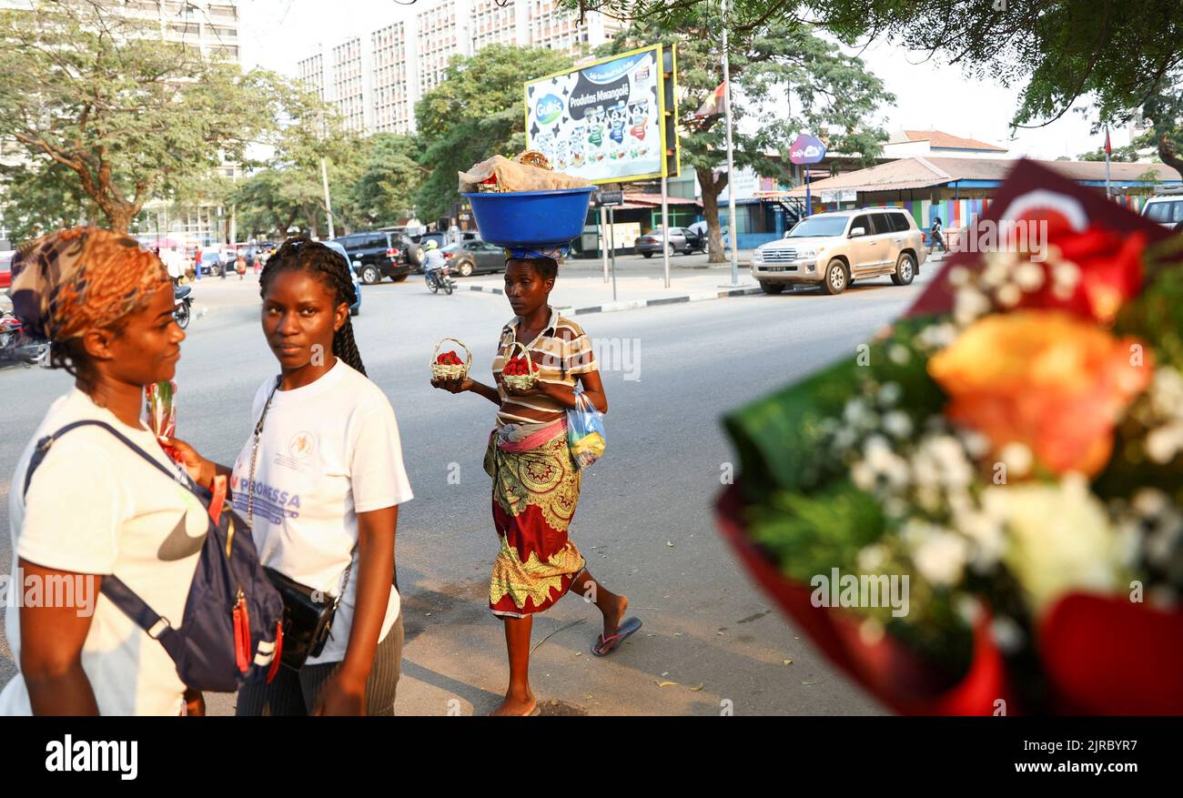 Locals walk past a flower vendor ahead of elections in the capital Luanda, Angola August 23, 2022. REUTERS/Siphiwe Sibeko Stock Photo