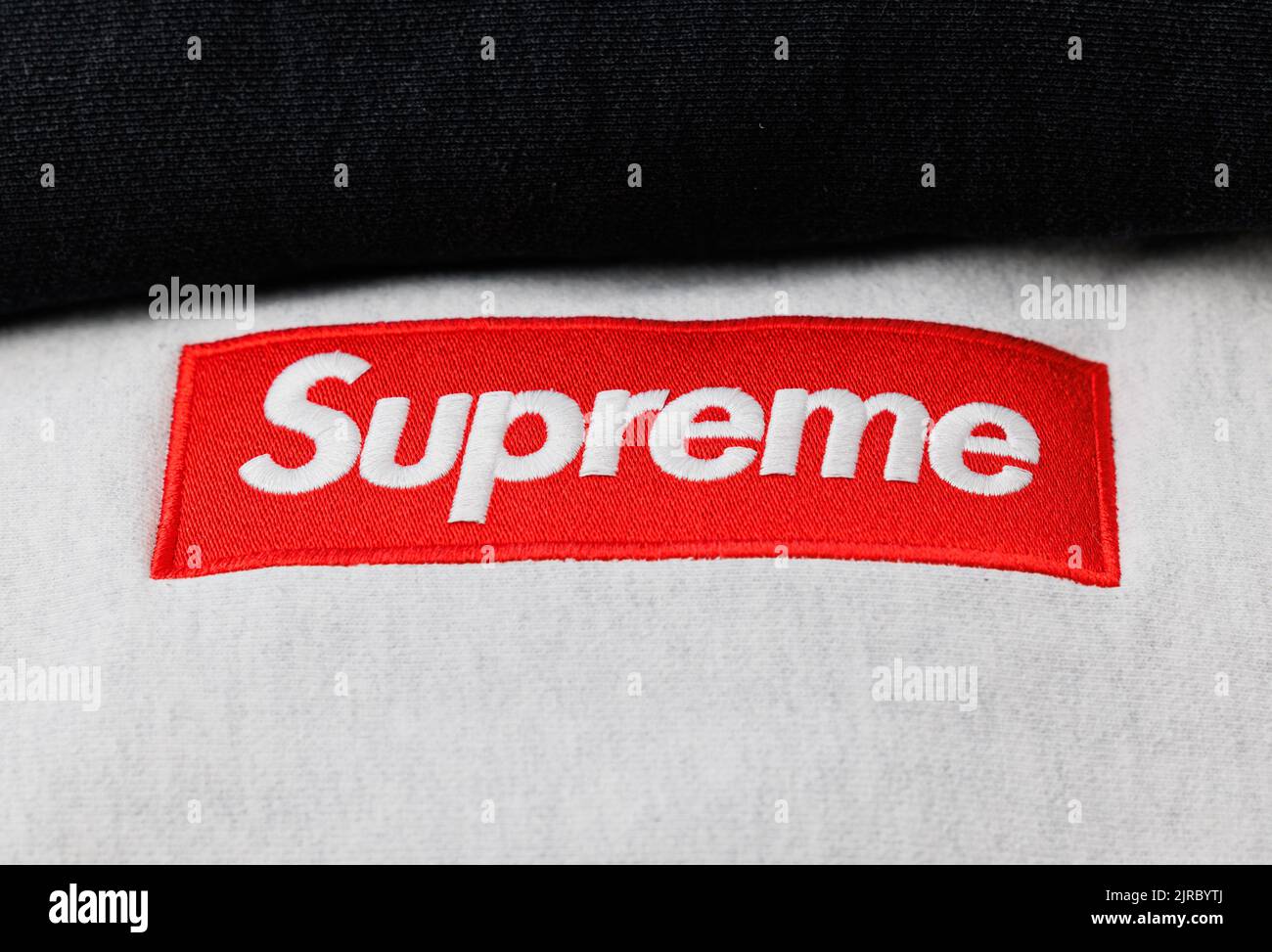 A closeup of a red patch with white Supreme stitching on a gray hoodie Stock Photo Alamy