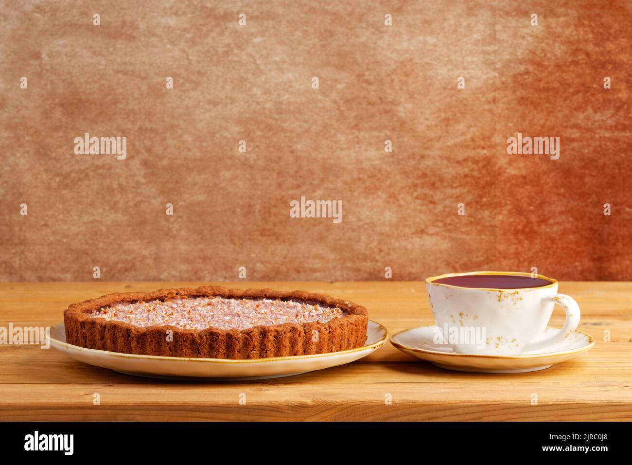 Homemade raspberry and banana pie and cup of tea on wooden table. Copyspace. Stock Photo