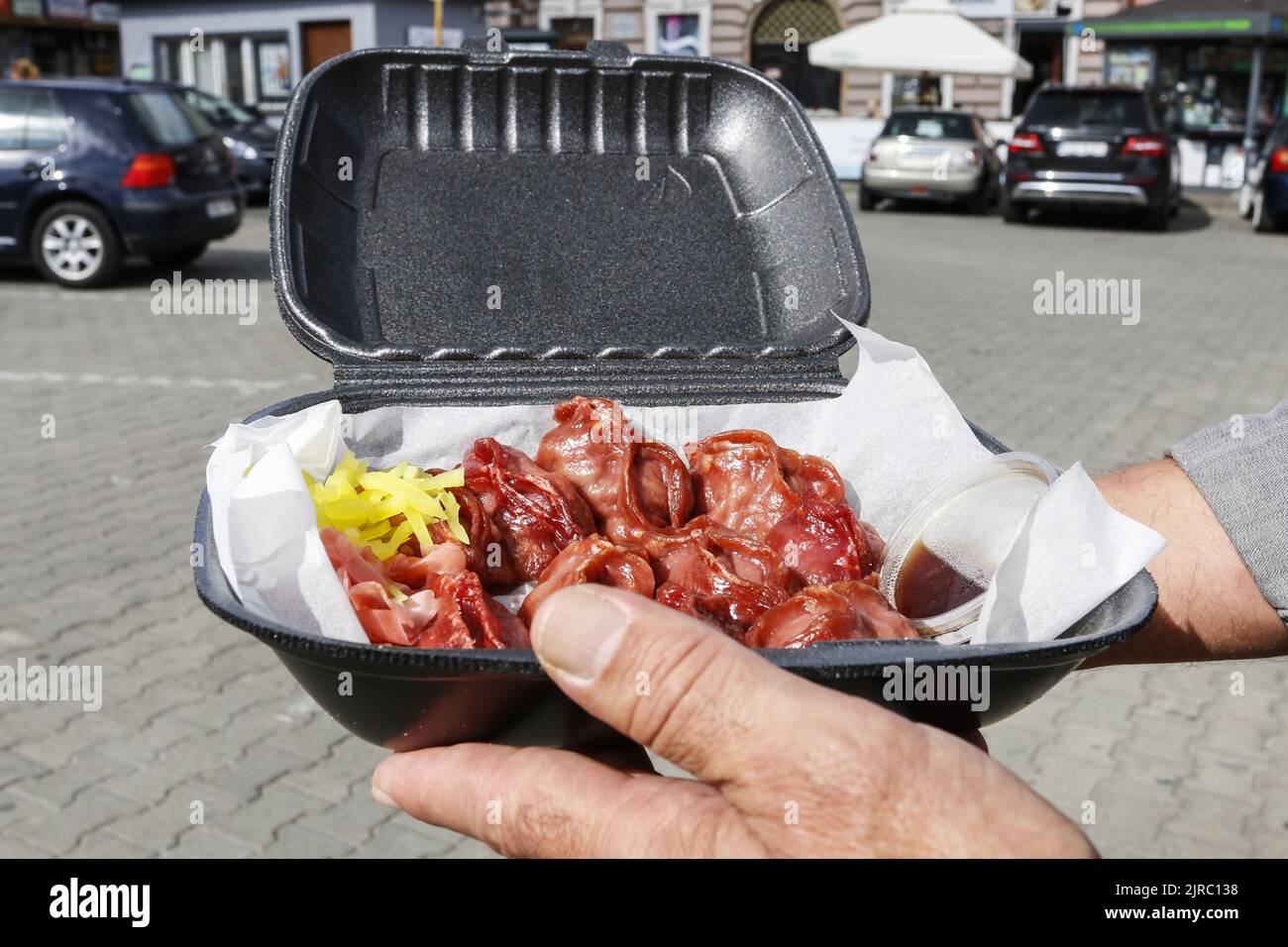 A man is holding a styrofoam tray with street food. Asian dumplings with hot sauce. Nonhealthy food Stock Photo