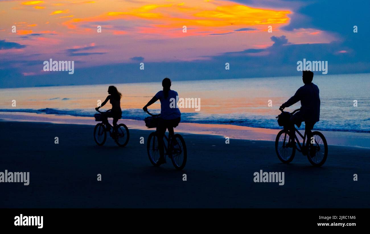 Family riding bikes on the beach on Hilton Head SC , sunrise Stock