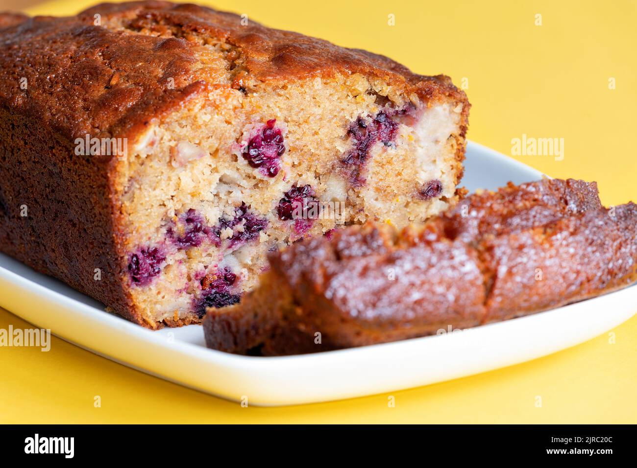 A freshly made Blackberry, apple and walnut cake. The cake has been made at home by the baker and is sliced showing the fruits inside the cake Stock Photo