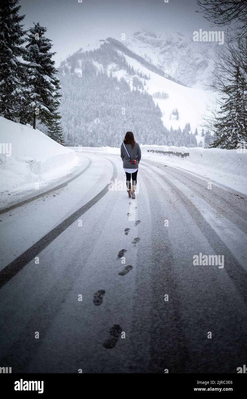 Frau geht auf der verschneiten Rossfeldpanoramastraße spazieren, Bayern, Deutschland. Stock Photo