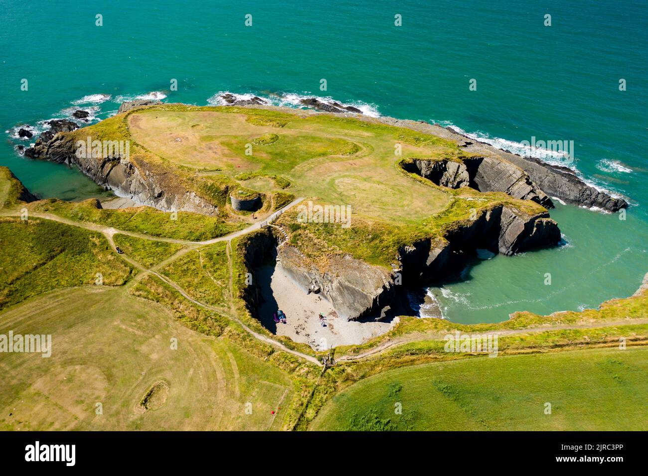 Aerial view of a tiny sandy beach surrounded by cliffs on the coast of Wales (Gwbert, Pembrokeshire) Stock Photo