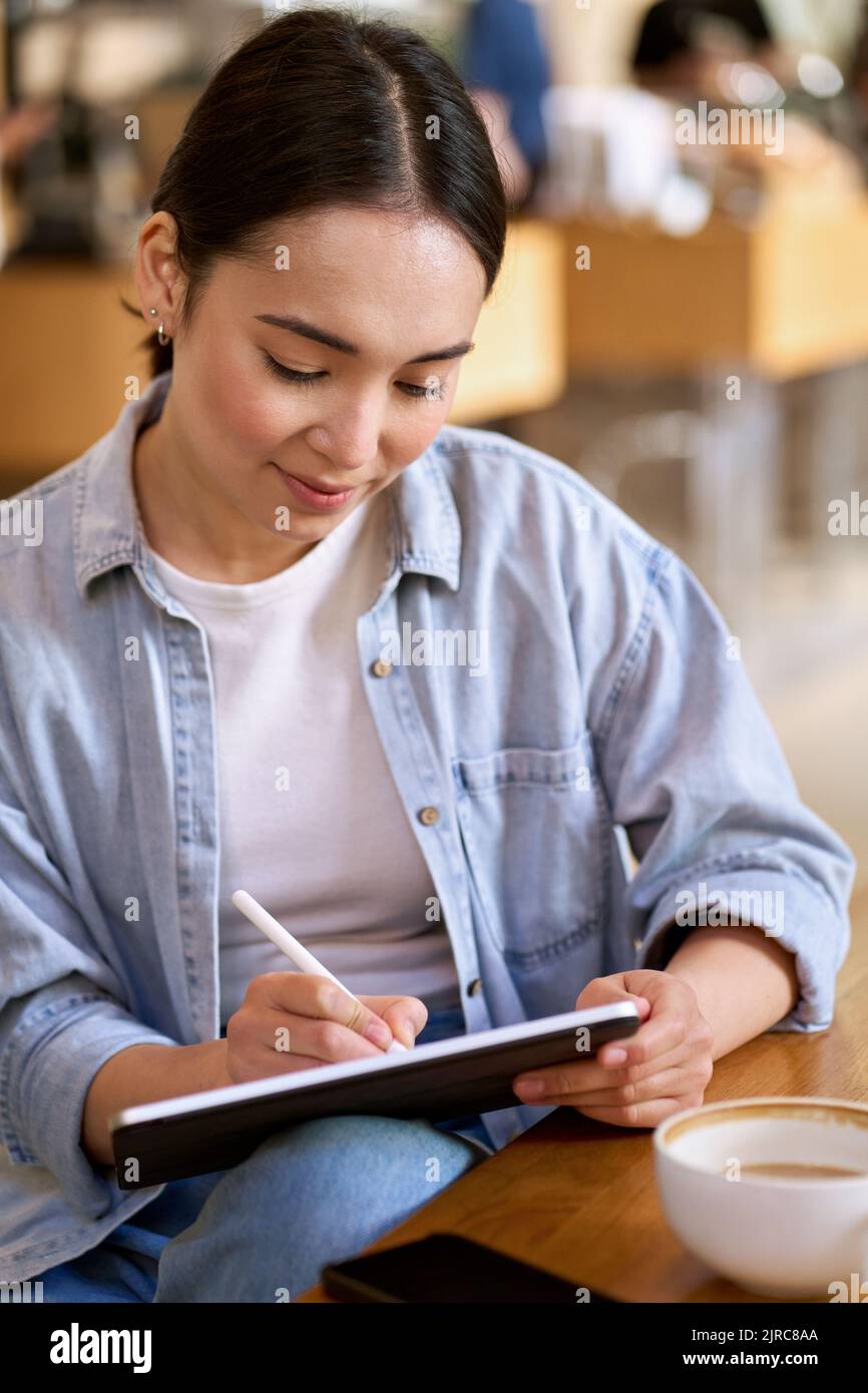 Young Asian woman student using digital tablet for elearning. Stock Photo