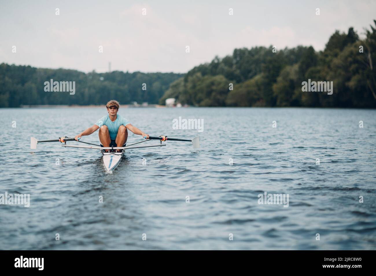 Sportsman single scull man rower rowing technique on boat. Paddle oar