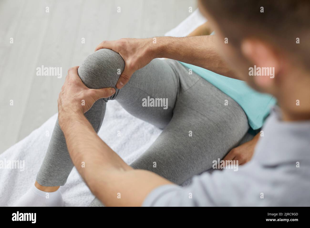 Physiotherapist or chiropractor at physiotherapy clinic examining patient's knee Stock Photo