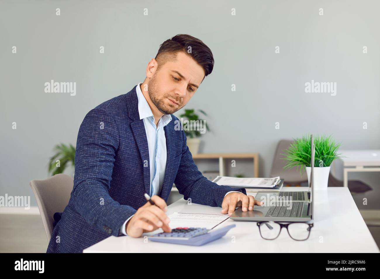 Serious businessman in office calculates monthly expenses, taxes and