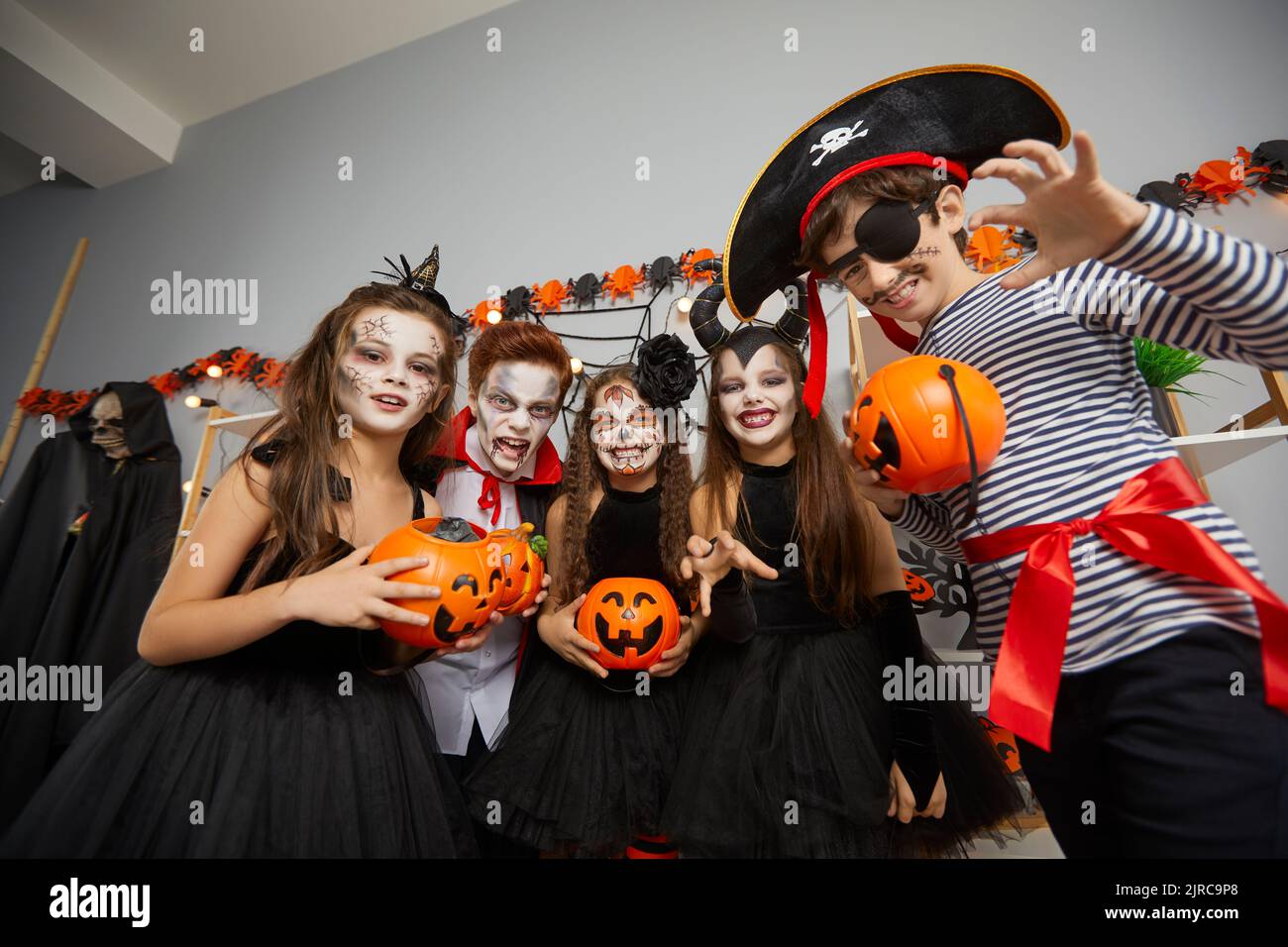 Group of children friends in carnival costumes and with spooky makeup at Halloween celebration. Stock Photo
