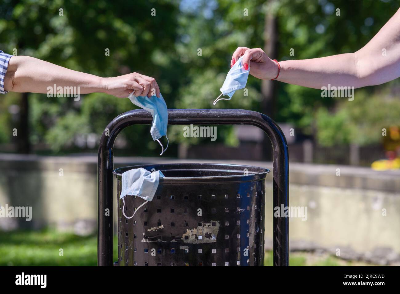 Throw away the mask in the trash can, medical mask in hand in front of