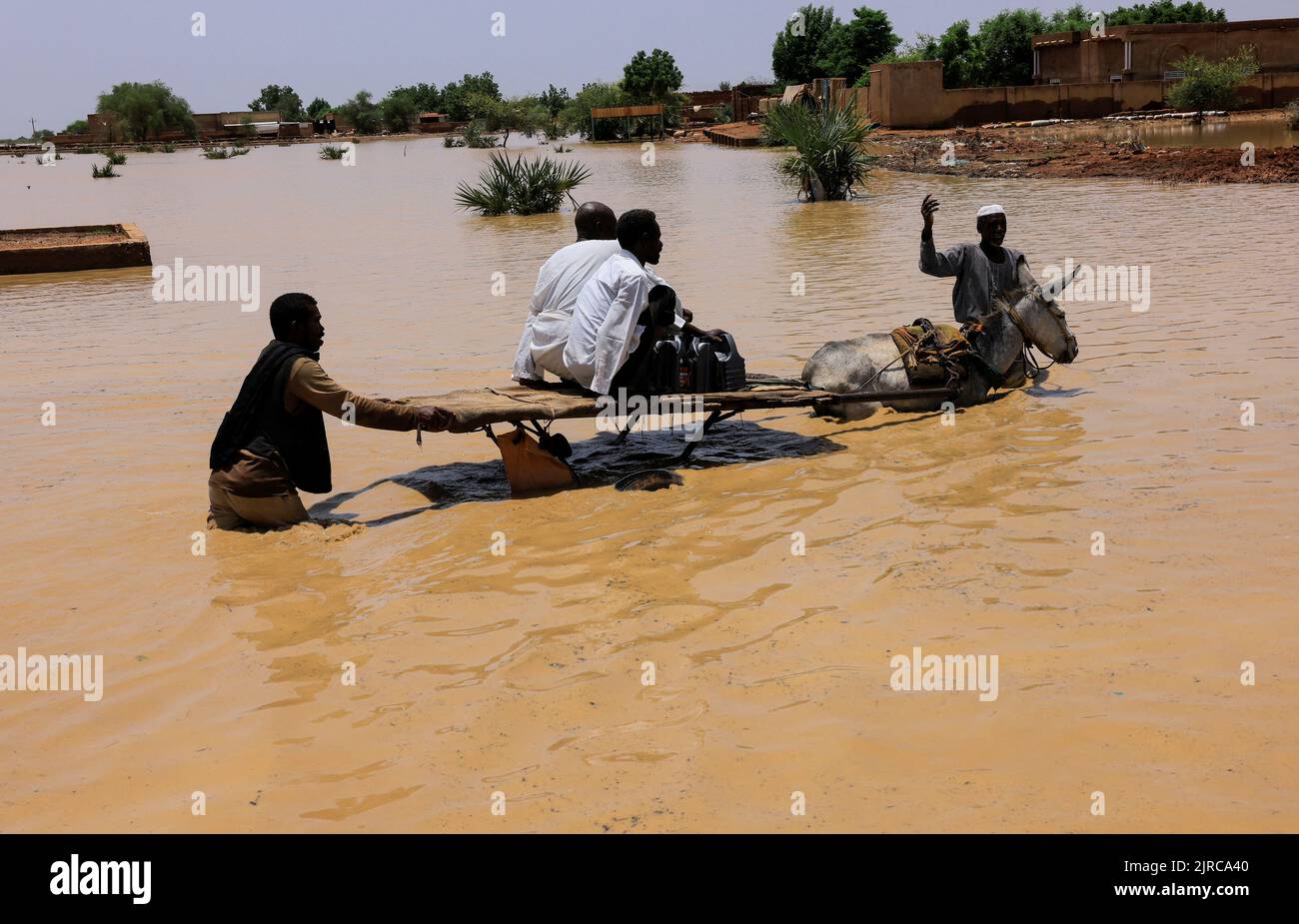 People ride a donkey cart to cross the water during flood in Al-Managil locality in Jazeera State, Sudan, August 23, 2022. REUTERS/Mohamed Nureldin Abdallah Stock Photo