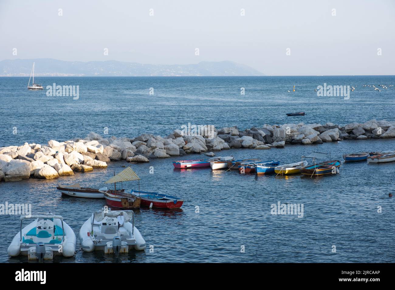 wide angle view of Naples coast with rocks, sea and boats Stock Photo
