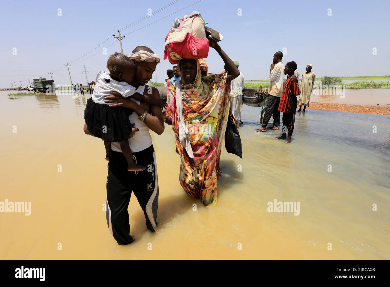 People cross water during flood in Al-Managil locality in Jazeera State, Sudan, August 23, 2022. REUTERS/Mohamed Nureldin Abdallah Stock Photo