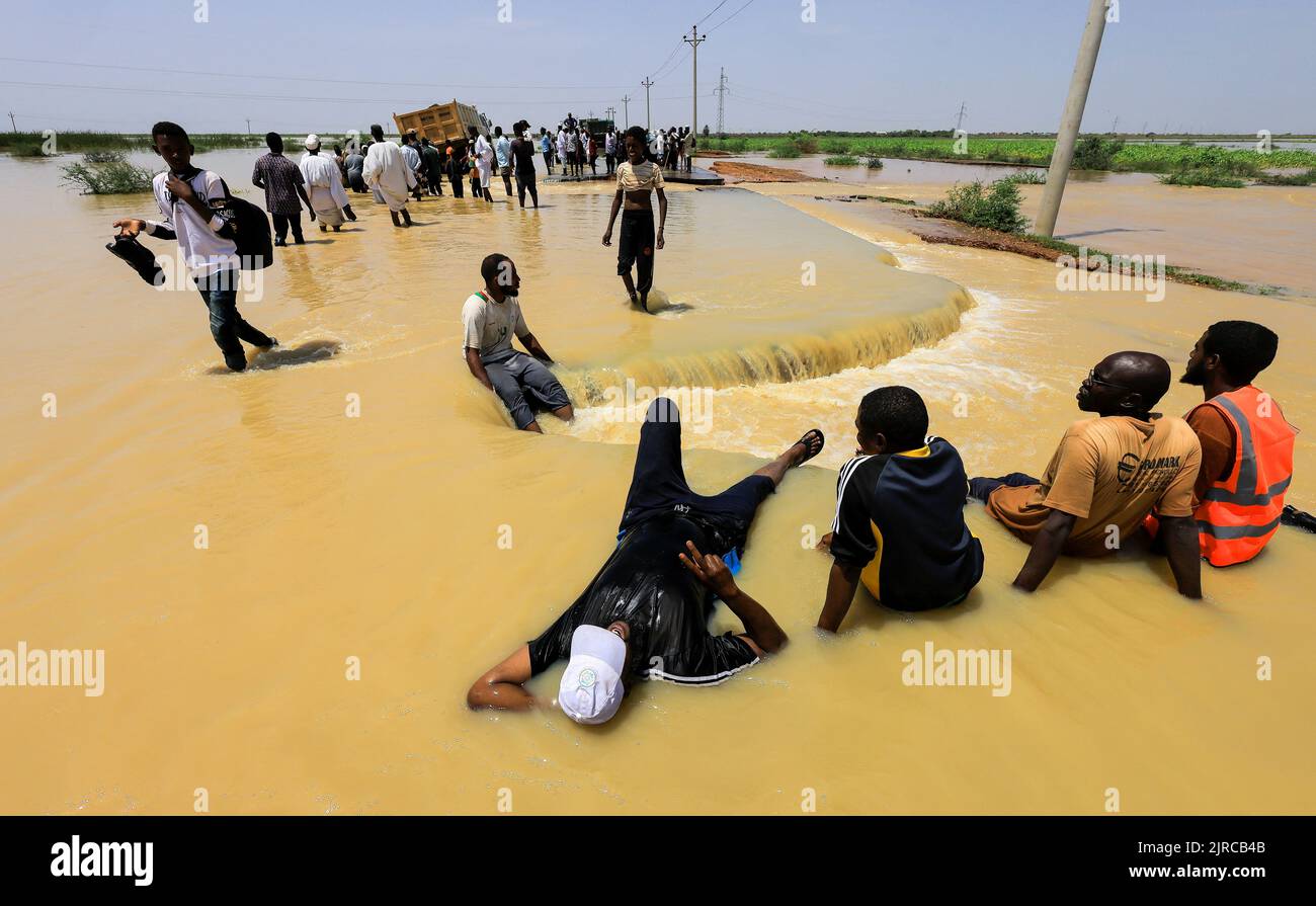 People rest as others cross the water during floods in Al-Managil locality in Jazeera State, Sudan, August 23, 2022. REUTERS/Mohamed Nureldin Abdallah     TPX IMAGES OF THE DAY Stock Photo