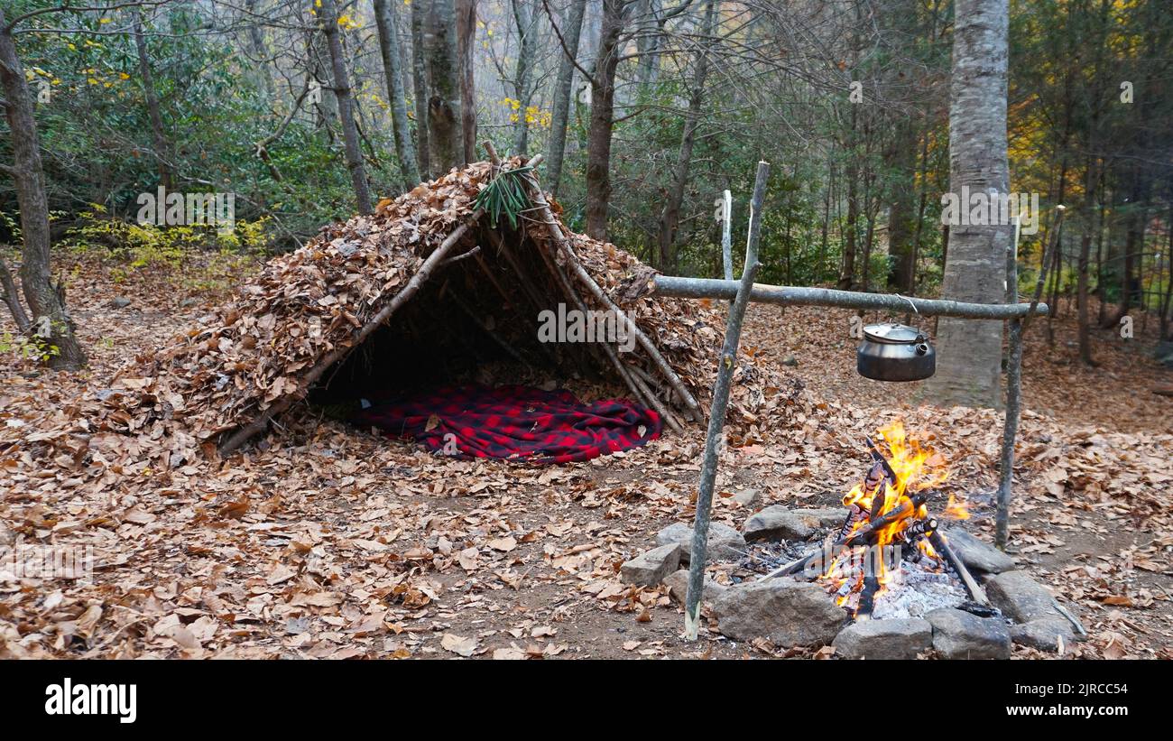 Bushcraft survival shelter in the wilderness. Debris hut camp site in the woods Stock Photo