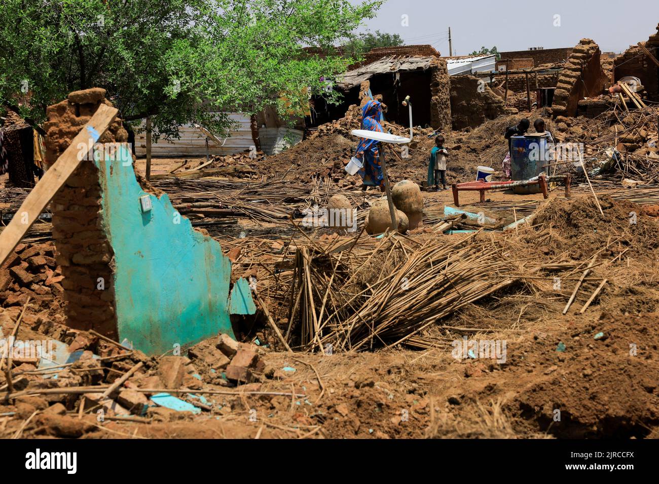 Family members stand in the ruins of their house, in Al-Managil locality during floods in Jazeera State, Sudan, August 23, 2022. REUTERS/Mohamed Nureldin Abdallah Stock Photo