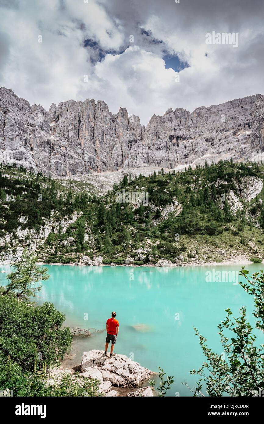Male backpacker enjoying turquoise Lago di Sorapiss mountain lake,Dolomites Mountains,Italy.Active people in nature.Limestone peaks,canyons,crystal Stock Photo
