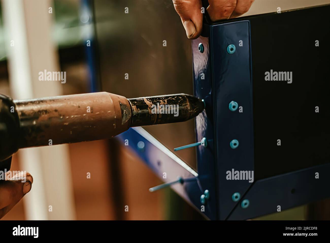 Male worker uses electric riveting gun. Hand holding riveting machine