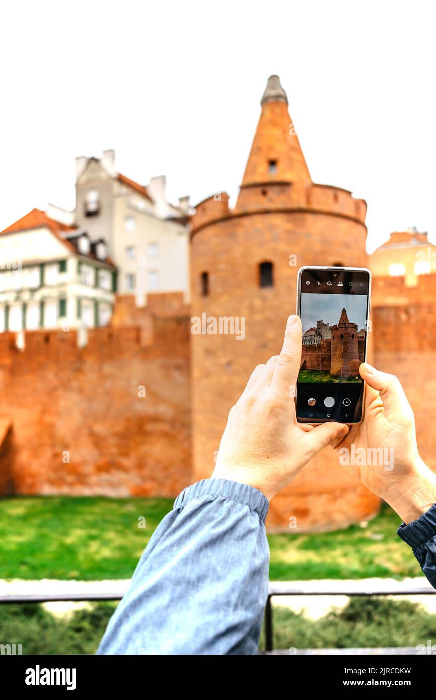 Man use smartphone to take Warsaw Barbican picture.Travel concept and technology.Tourist taking picture of a city.Man photographer making photos Stock Photo