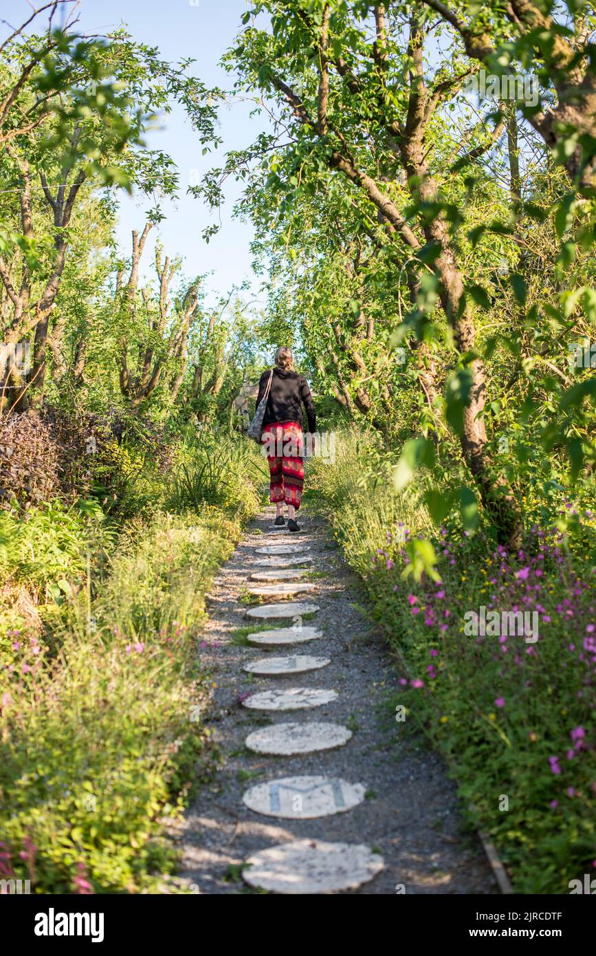 A woman walks up a path of round stones at an Eco Camp Stock Photo