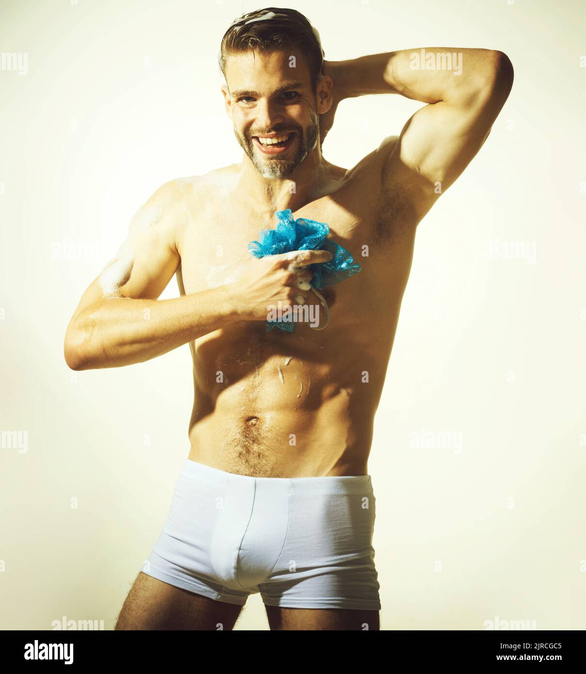 Sexy muscular man in boxer shorts take shower. Handsome guy with nude torso washes body in bathroom. Stock Photo