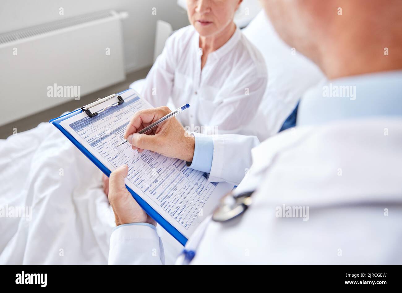 senior woman and doctor with clipboard at hospital Stock Photo - Alamy