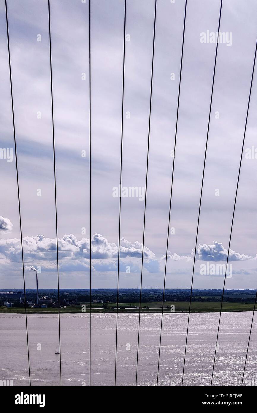 A vertical shot of a coastal city from a bridge with suspender cables Stock Photo