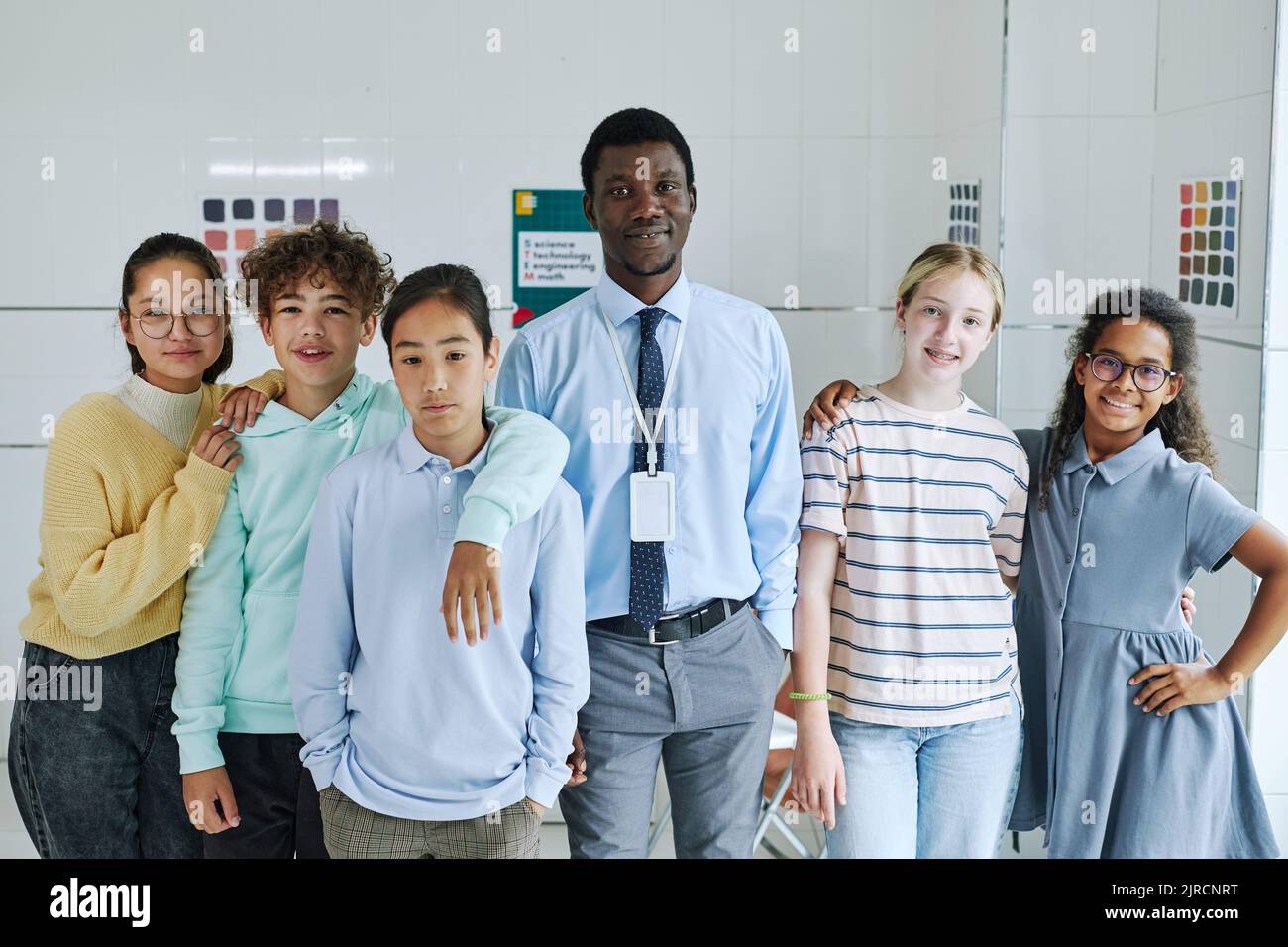 Diverse group of children with young male teacher looking at camera in mental health center Stock Photo