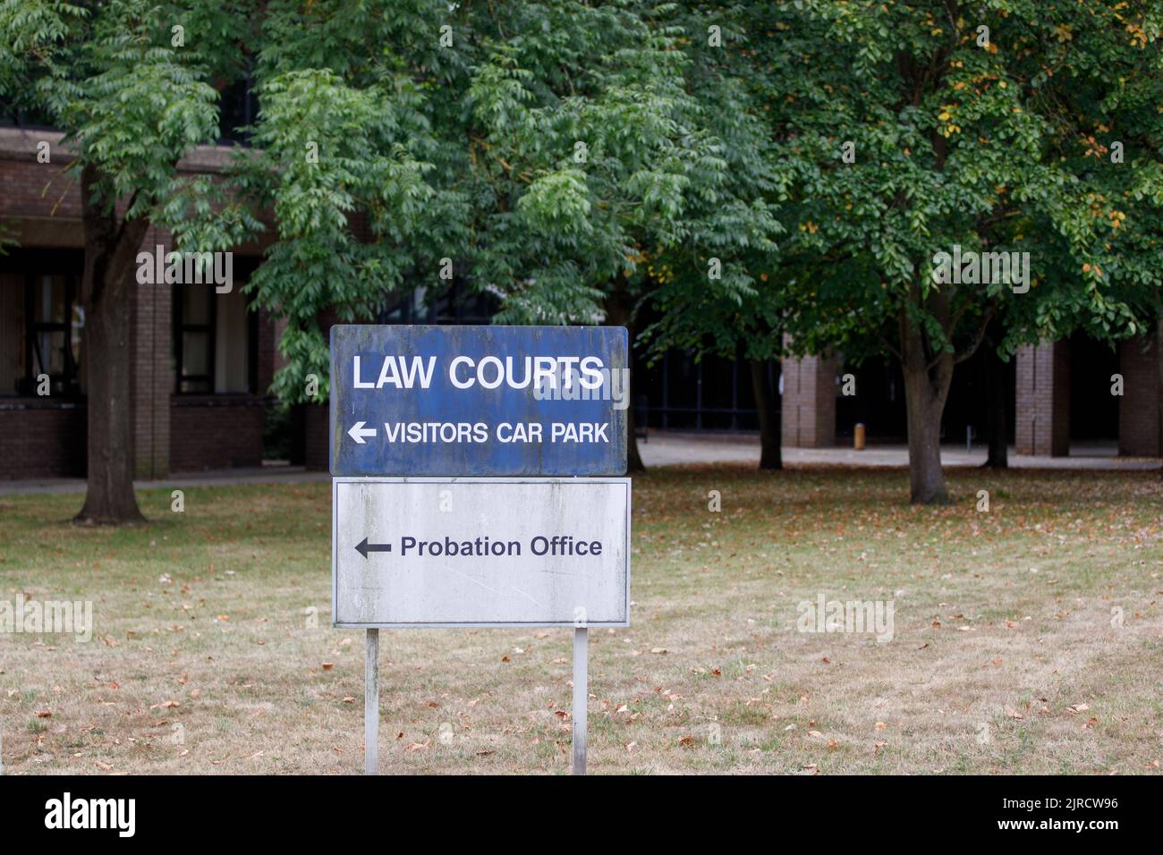 An English Law Courts and probation office sign board with trees and building blurred in the background. No people Stock Photo