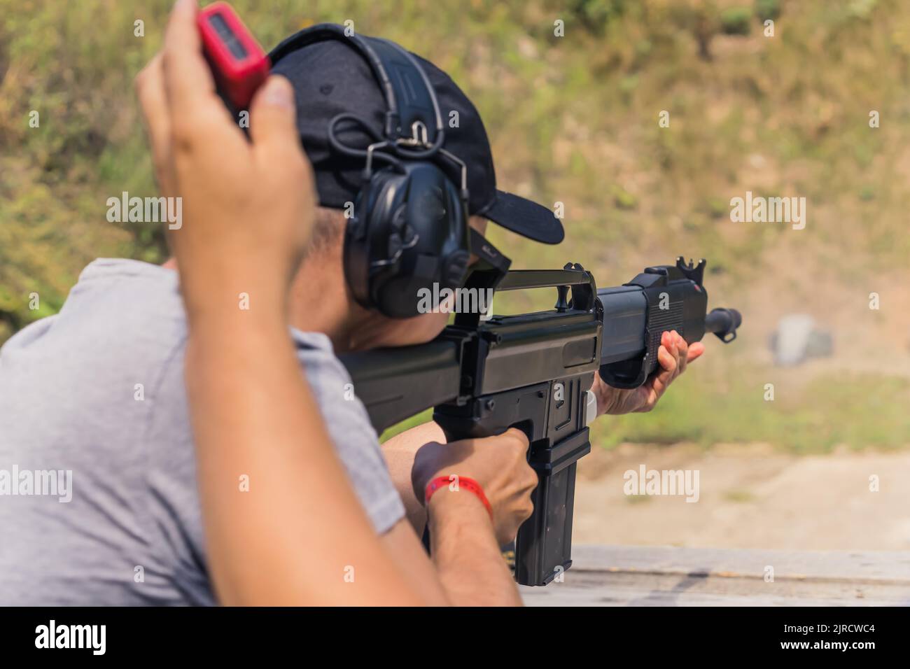 Rear view of man wearing safety headphones practicing firing shotgun on