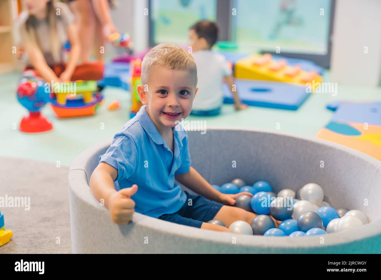 little blond boy playing with balls in the kindergarten. High quality photo Stock Photo