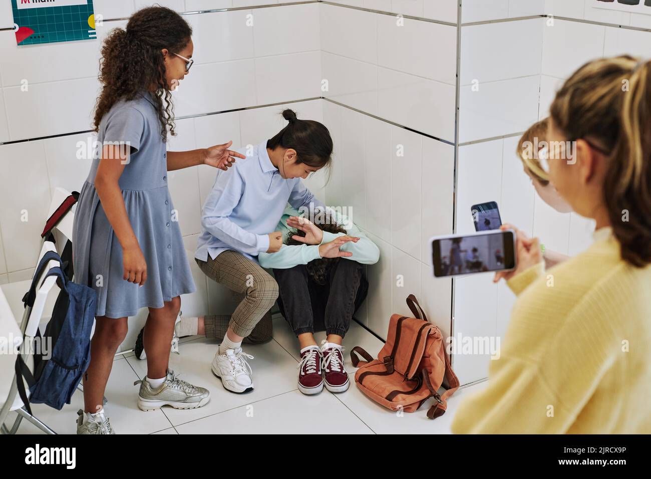 School bullying scene with teenage kids fighting in hallway and recording it on smartphone