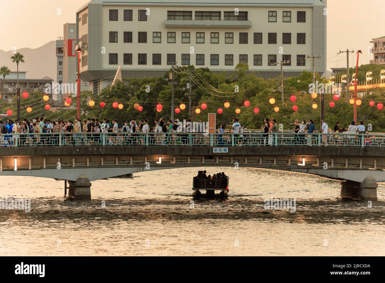 Tokushima, Japan - August 12, 2022: Small boat passes under crowded bridge at Awaodori Festival Stock Photo