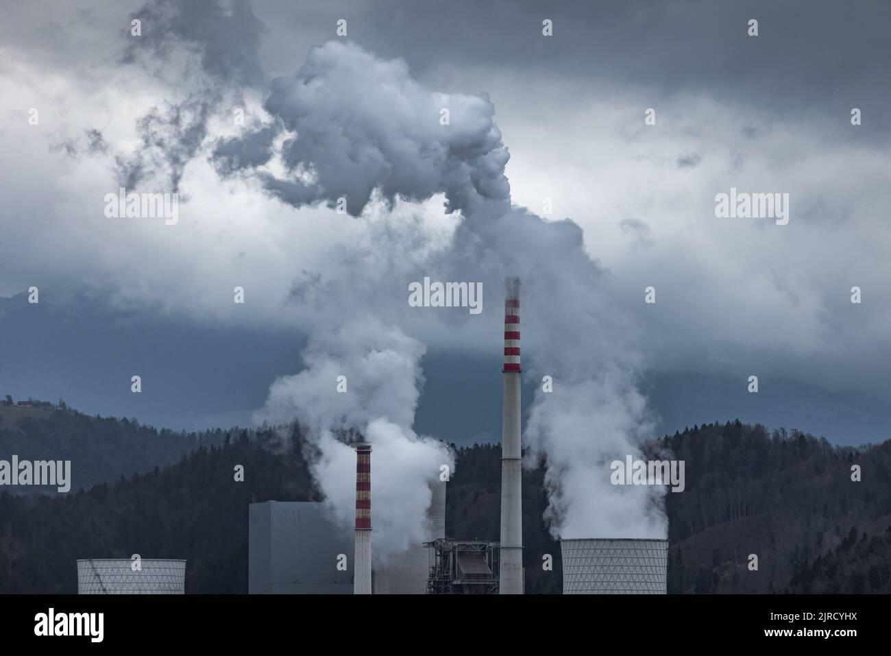 Thermal power plant burning coal with large cooling tower, emitting