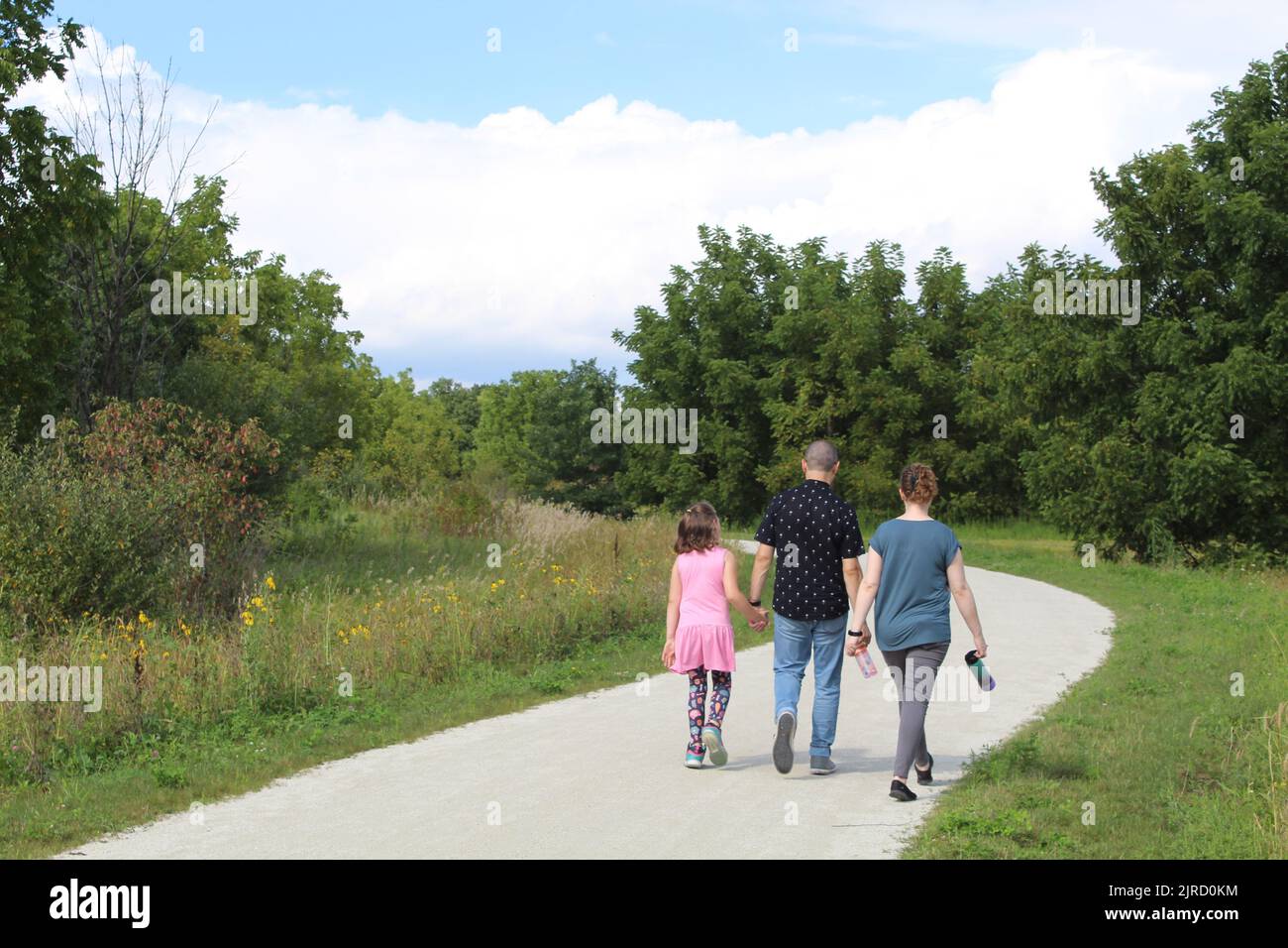 Mother, father, and daughter walking on a trail in the woods at Blackwell Forest Preserve in Warrenville, Illinois Stock Photo