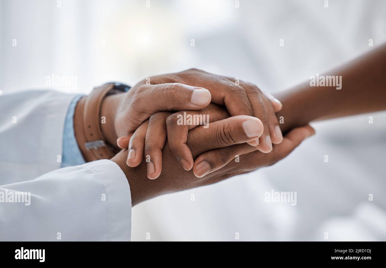 Support, trust and hospital care with a doctor and patient holding hands, sharing bad news of a cancer diagnosis. Kind doctor offering a loving Stock Photo