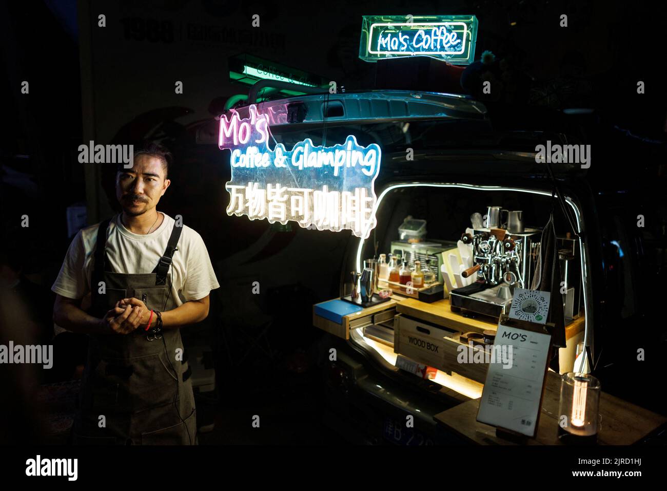 Wang Wei stands next to his coffee bar that he installed in the back of his car at a car boot fair in Beijing, China, August 13, 2022. REUTERS/Thomas Peter Stock Photo
