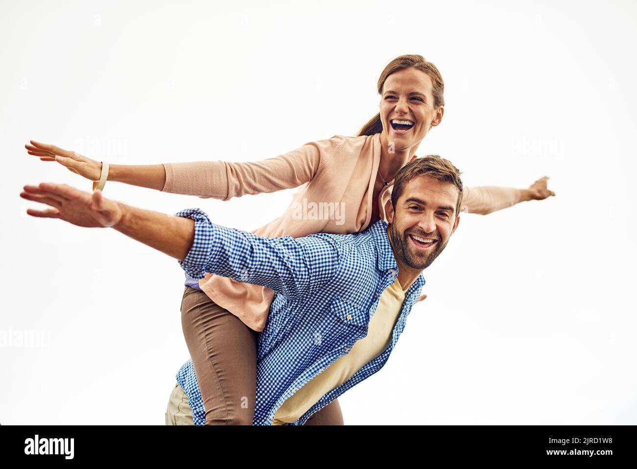 Enjoying our freedom. a man piggybacking his girlfriend while spending the day outdoors. Stock Photo