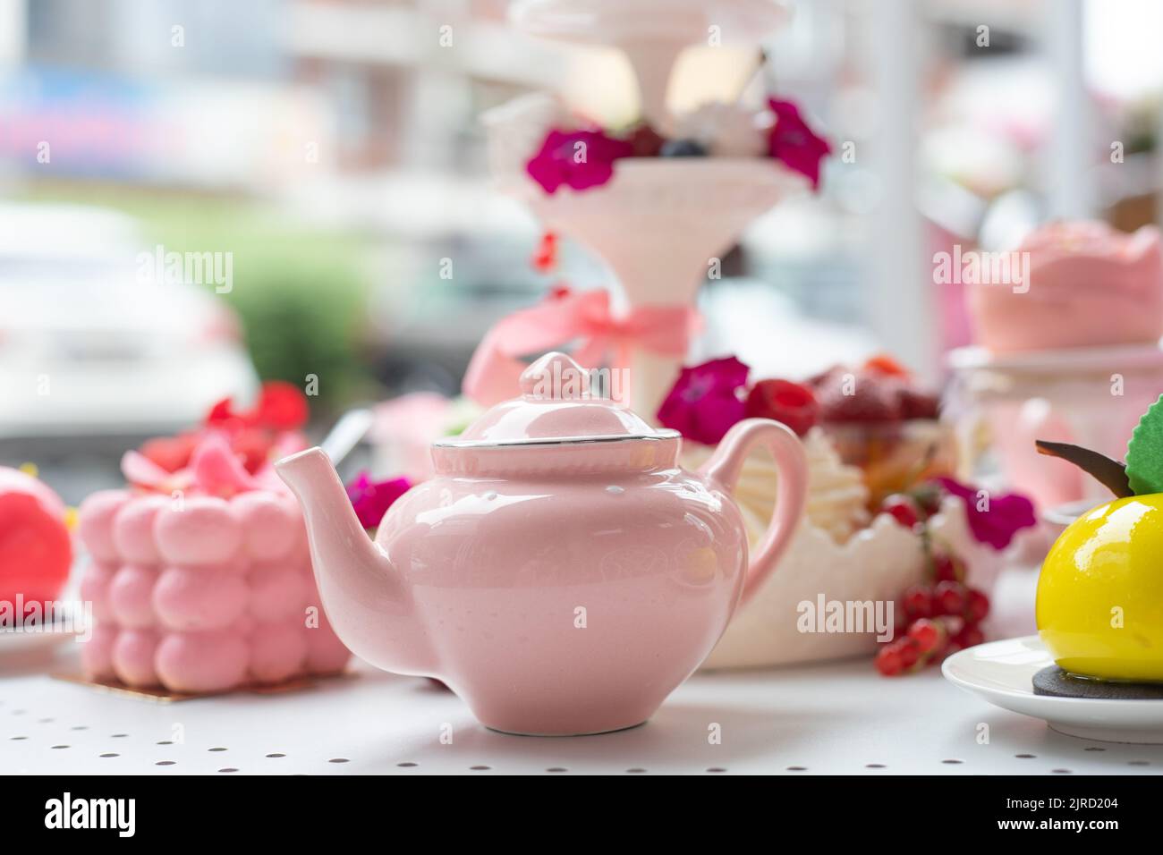 Abundance of close up pink sweet desserts, teapot on table. Opening of