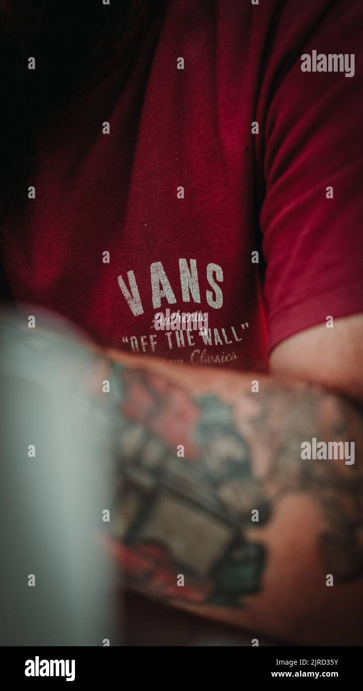 A vertical shot of VANS brand logo on a man wearing red T-shirt Stock Photo