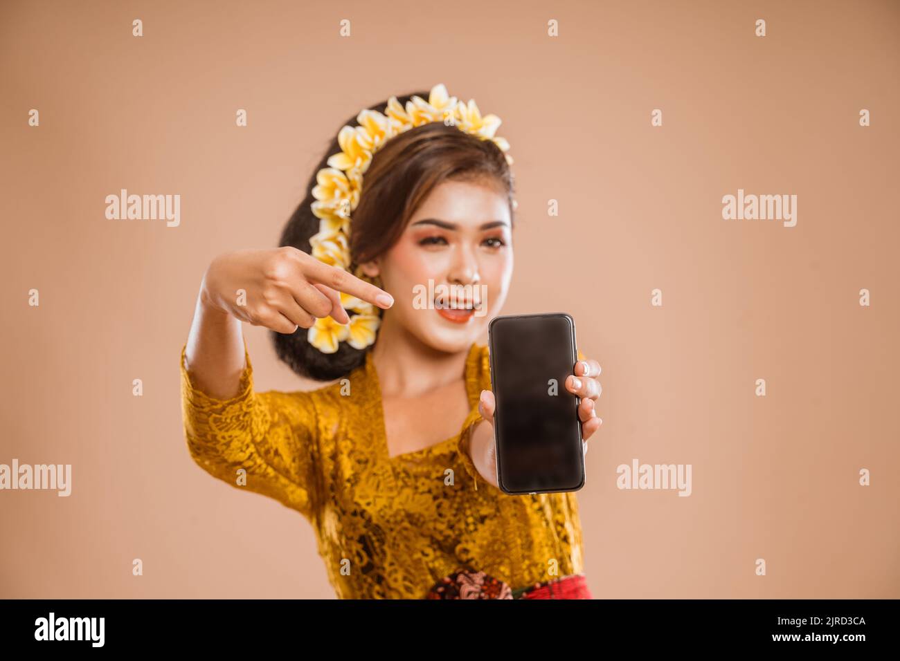 balinese woman with kebaya showing her mobile phone screen to camera Stock Photo