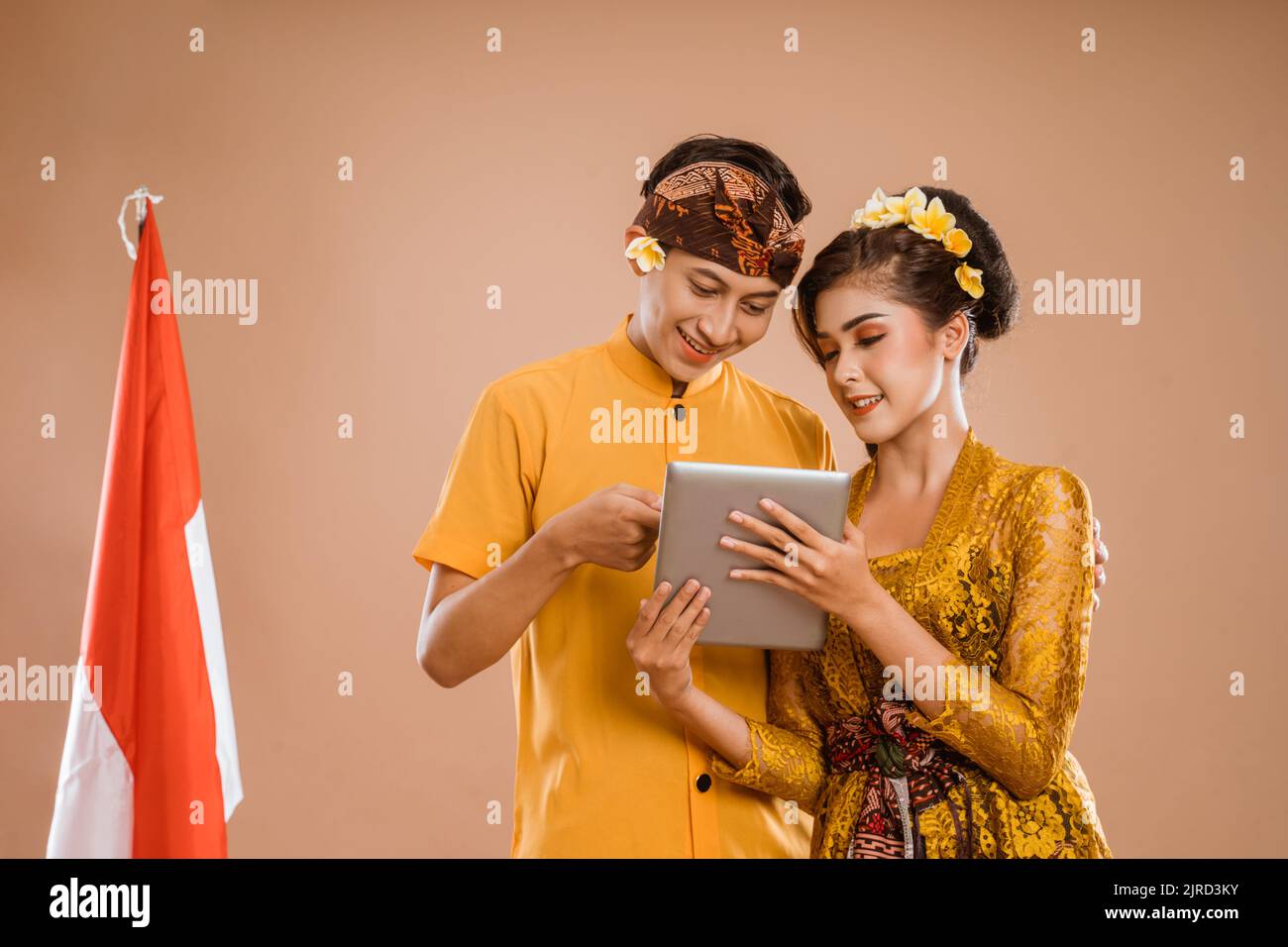 man and woman wearing balinese traditional clothing using tablet Stock Photo
