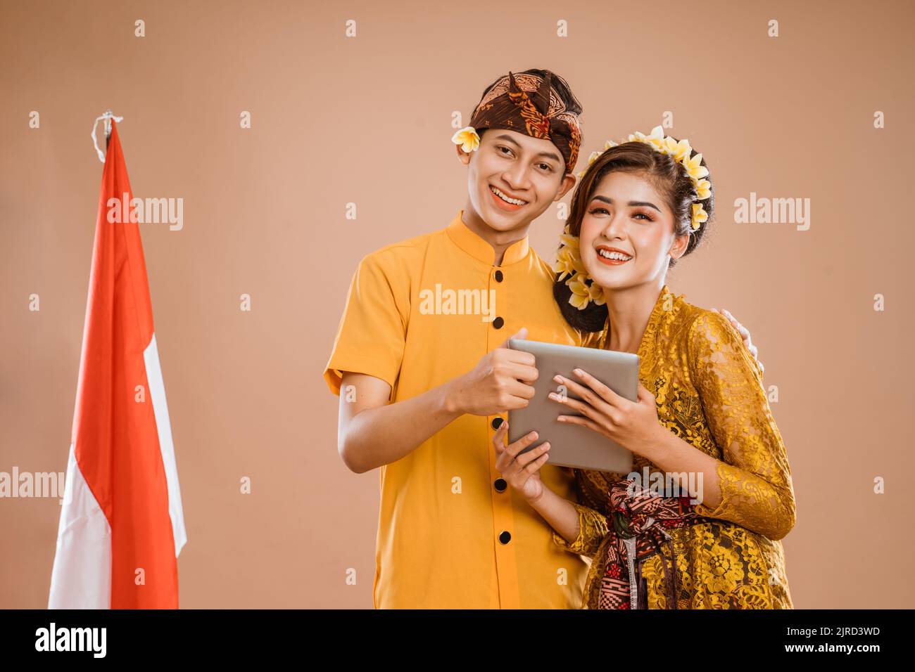 man and woman wearing balinese traditional clothing using tablet Stock Photo