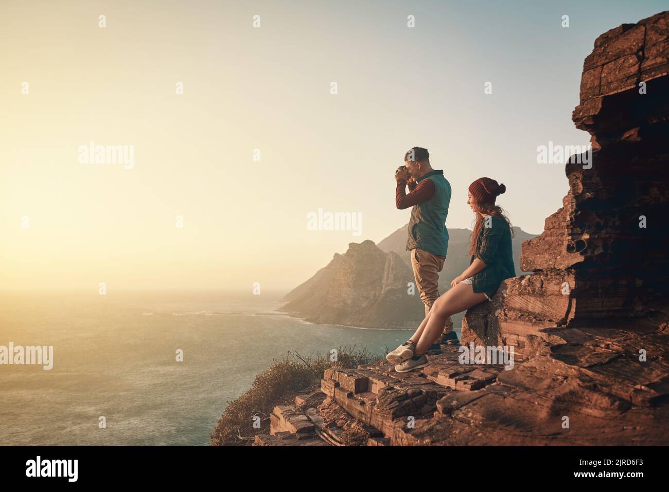 Some views demand a photograph. Full length shot of a young man taking picture of the view while hiking with his girlfriend. Stock Photo