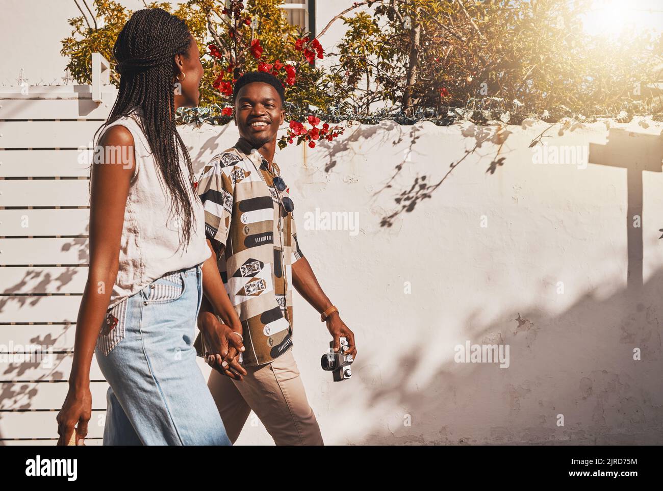 Young love couple walking in summer, sun and fresh outdoor air together in neighborhood with lens flare. Happy, smile and content black people holding Stock Photo